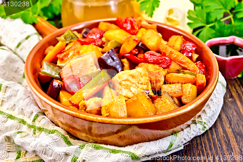 Image of Roast with vegetables and honey in pan on dark board