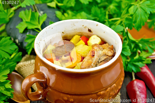 Image of Roast meat and vegetables in pot on dark board