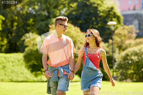 Image of happy teenage couple walking at summer park