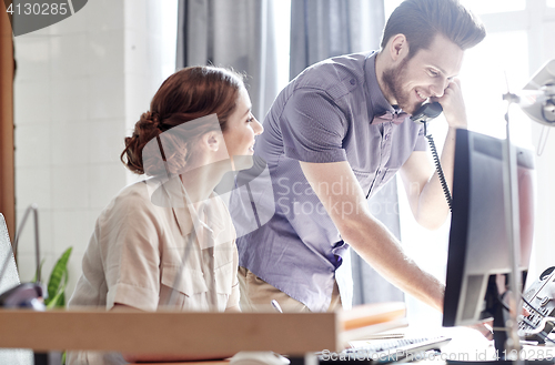 Image of happy creative team calling on phone in office