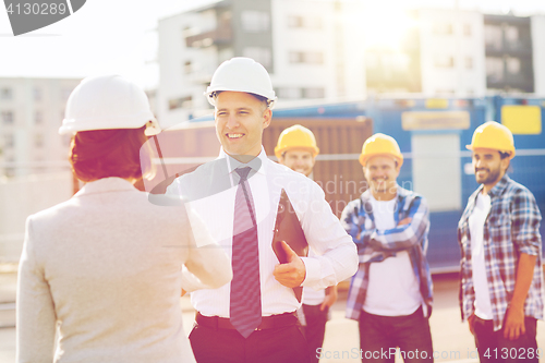 Image of group of smiling builders in hardhats outdoors