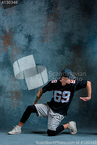 Image of Young man break dancing on wall background.