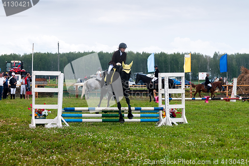 Image of Young girl rider on a horse overcomes obstacles