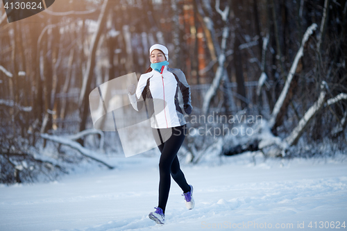 Image of Young sportswoman running among trees