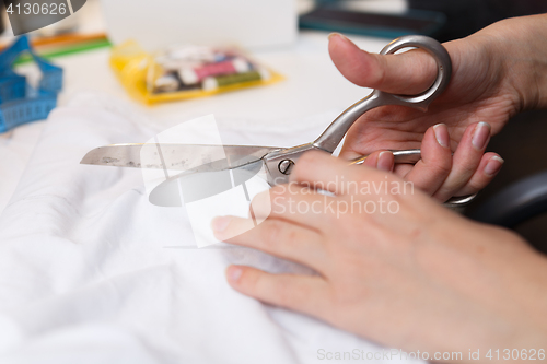 Image of Seamstress cuts cloth pair scissors