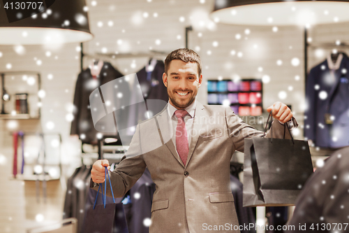 Image of happy man with shopping bags at clothing store