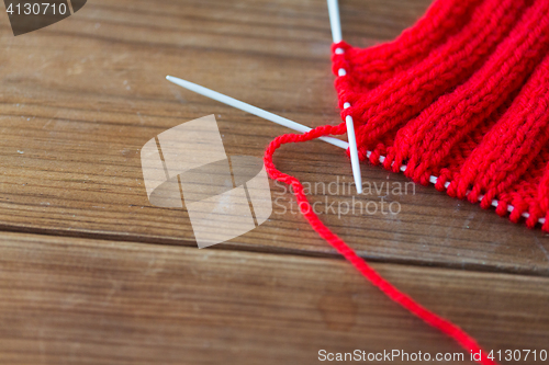 Image of hand-knitted item with knitting needles on wood