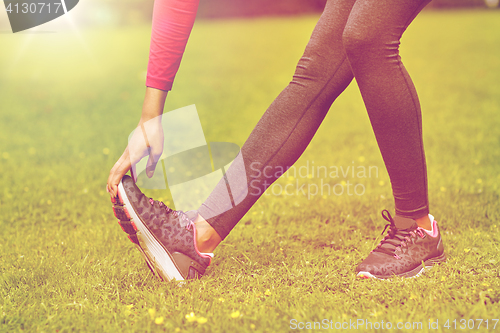 Image of close up of woman stretching leg outdoors