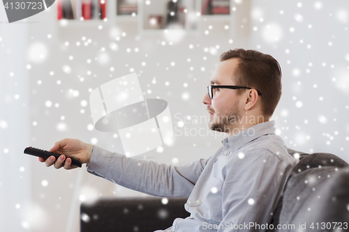 Image of smiling man with tv remote control at home