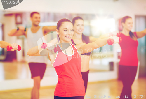 Image of group of smiling people working out with dumbbells