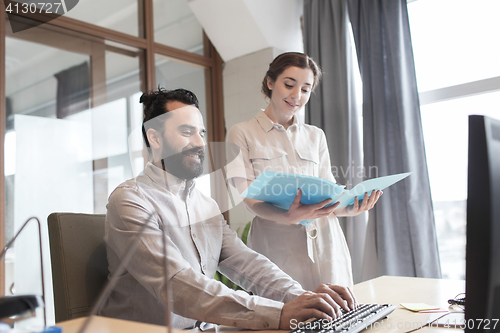 Image of happy creative team with computer in office