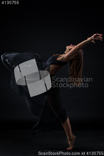 Image of Young beautiful dancer in beige dress dancing on black background