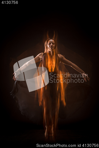 Image of Young beautiful dancer in beige dress dancing on black background