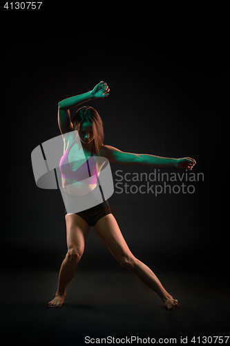 Image of Young beautiful dancer in beige dress dancing on black background