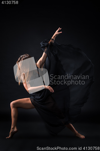 Image of Young beautiful dancer in beige dress dancing on black background