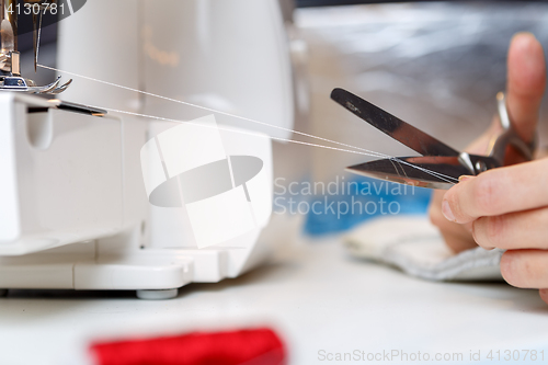 Image of Seamstress shortens thread with scissors