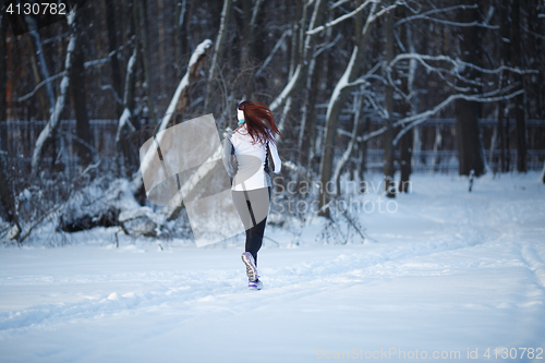 Image of Young woman running among trees