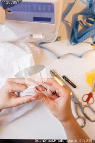 Image of Seamstress in atelier unrips fabric