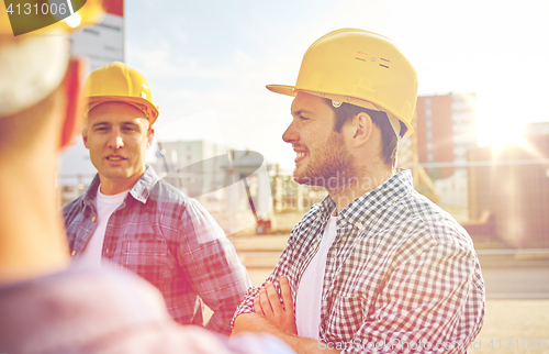 Image of group of smiling builders in hardhats outdoors