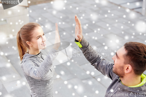 Image of couple of sportsmen making high five outdoors