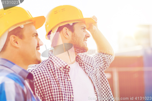 Image of group of smiling builders in hardhats outdoors