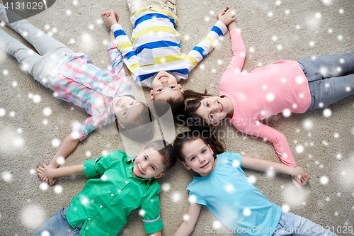 Image of happy smiling children lying on floor over snow