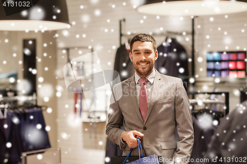 Image of happy man with shopping bags at clothing store