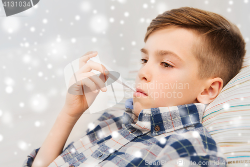 Image of ill boy with flu and thermometer at home