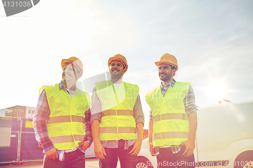 Image of happy male builders in high visible vests outdoors