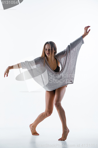 Image of Young beautiful dancer in beige dress dancing on white background