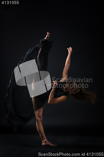 Image of Young beautiful dancer in beige dress dancing on black background