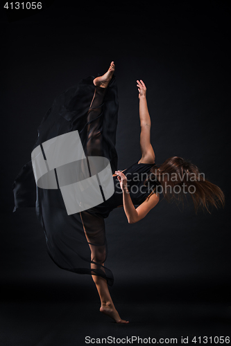 Image of Young beautiful dancer in beige dress dancing on black background