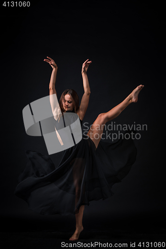 Image of Young beautiful dancer in beige dress dancing on black background