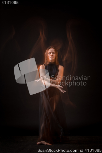 Image of Young beautiful dancer in beige dress dancing on black background