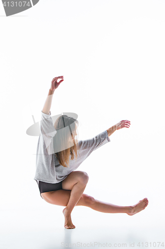 Image of Young beautiful dancer in beige dress dancing on white background