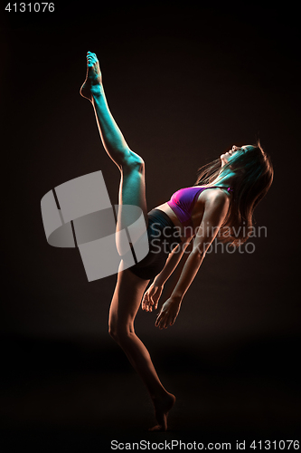 Image of Young beautiful dancer in beige dress dancing on black background