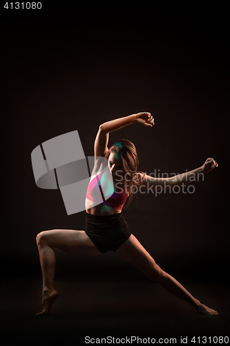 Image of Young beautiful dancer in beige dress dancing on black background