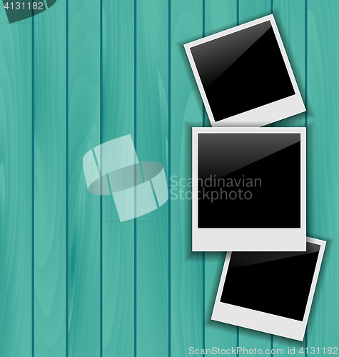 Image of Three blank photo frames on wooden background