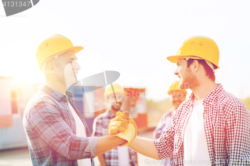 Image of group of smiling builders in hardhats outdoors