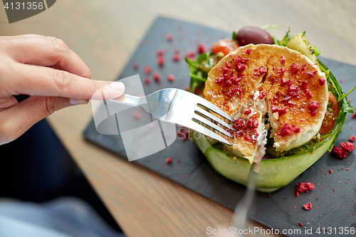 Image of woman eating goat cheese salad at restaurant