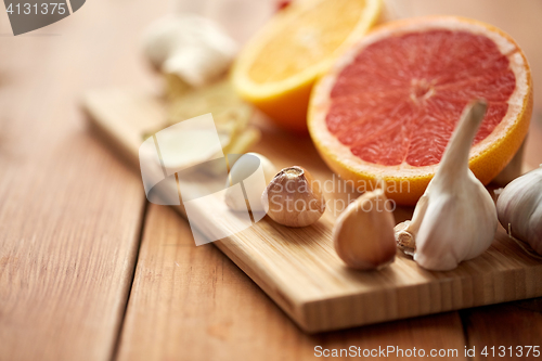 Image of garlic, grapefruit, ginger, and orange on board