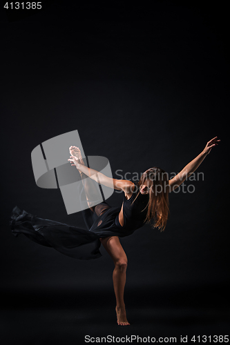 Image of Young beautiful dancer in beige dress dancing on black background