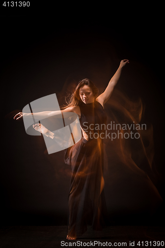 Image of Young beautiful dancer in beige dress dancing on black background