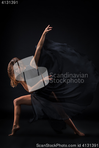 Image of Young beautiful dancer in beige dress dancing on black background