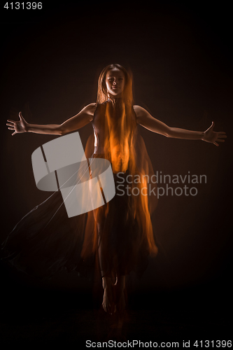 Image of Young beautiful dancer in beige dress dancing on black background