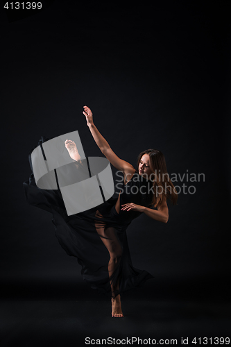 Image of Young beautiful dancer in beige dress dancing on black background