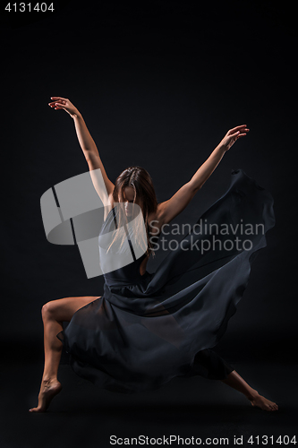 Image of Young beautiful dancer in beige dress dancing on black background