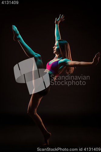 Image of Young beautiful dancer in beige dress dancing on black background