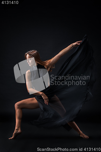 Image of Young beautiful dancer in beige dress dancing on black background