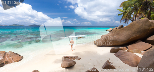 Image of Woman enjoying Anse Patates picture perfect beach on La Digue Island, Seychelles.